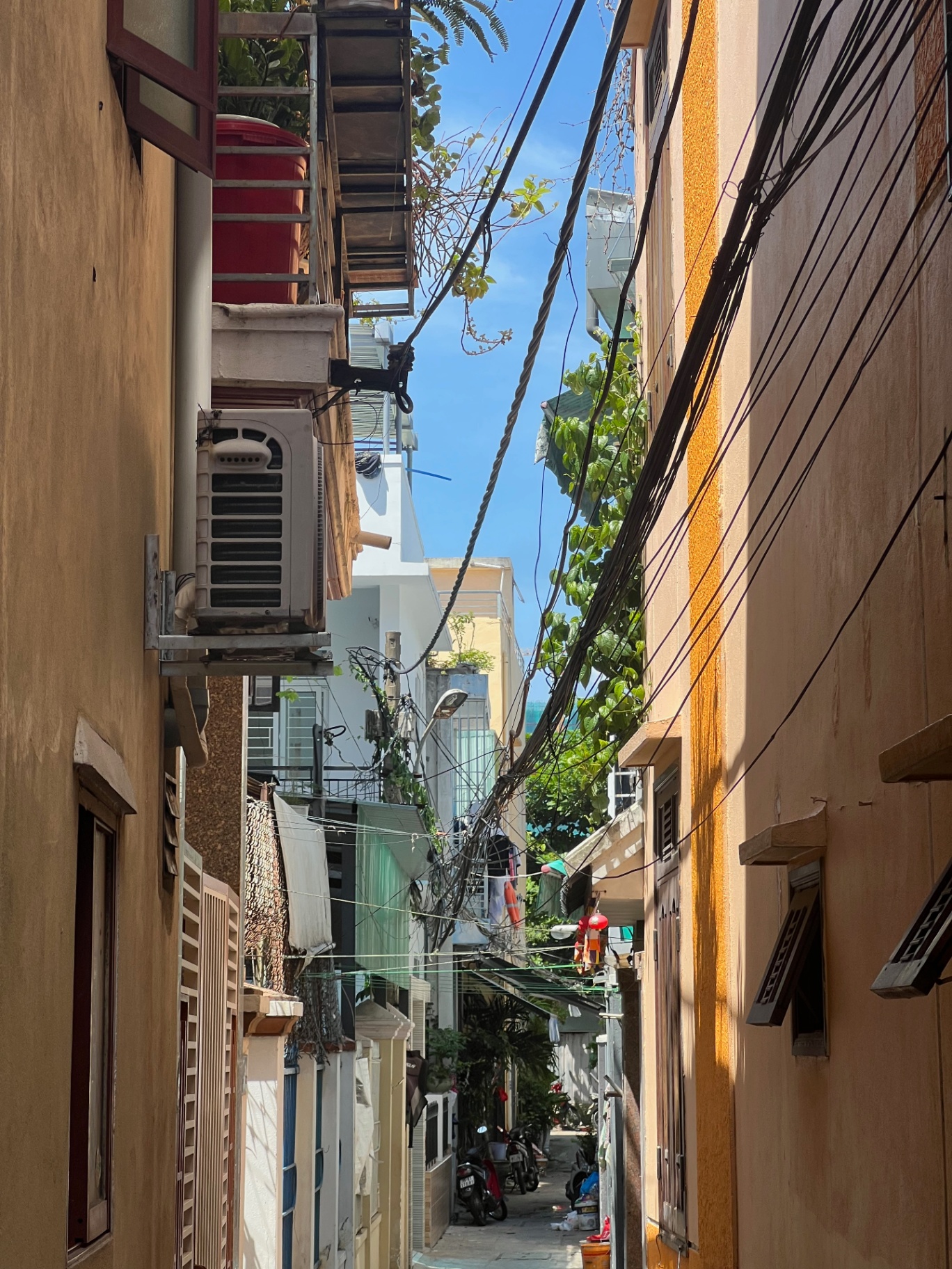 Da Nang — A narrow Da Nang alley tangled with wires under the midday sun.
