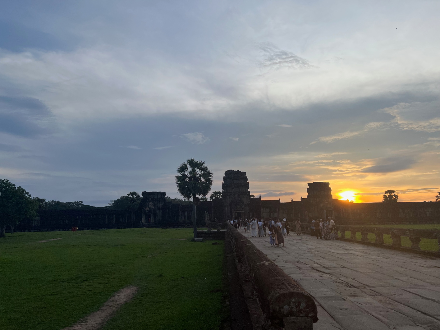 Siem Reap — Crowds drifting along the outer wall as the sun drops.