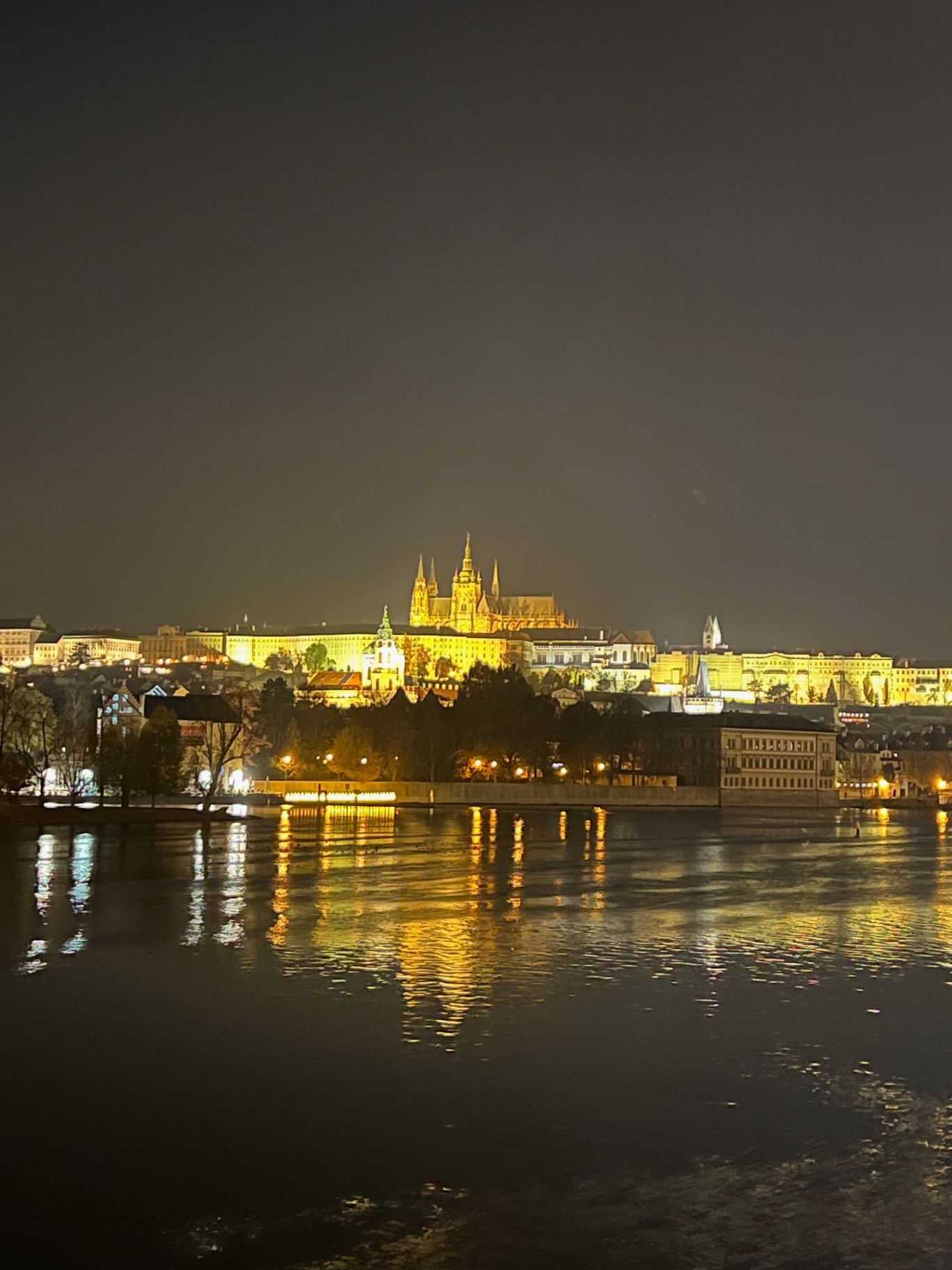 Prague — Prague Castle lit gold above the Vltava at night.