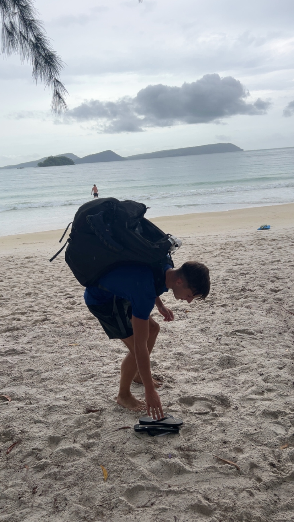 Koh Rong — Backpack on, picking up flip flops as we arrive on the island.