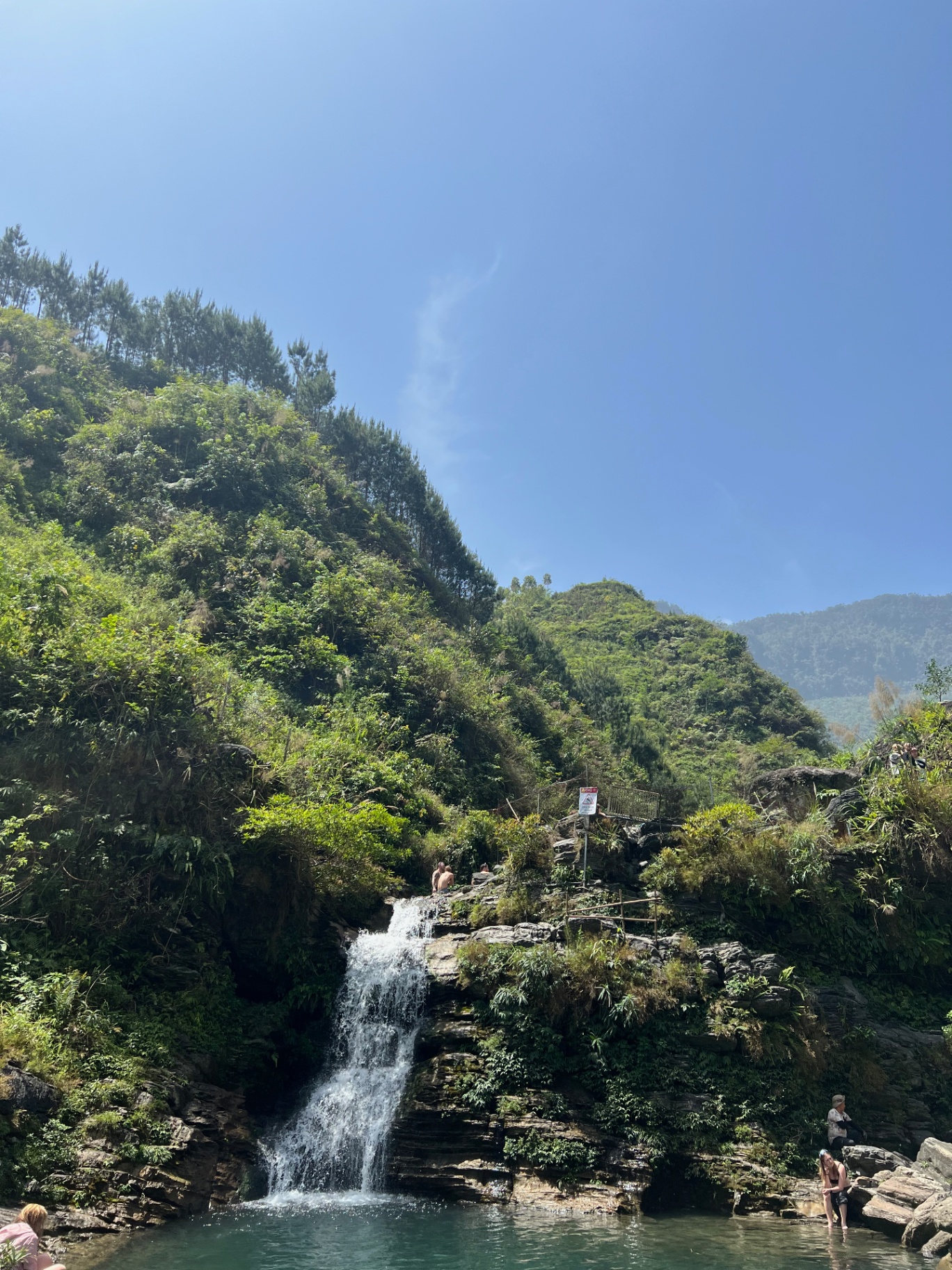 Ha Giang — A waterfall tucked into the jungle on a clear blue afternoon.