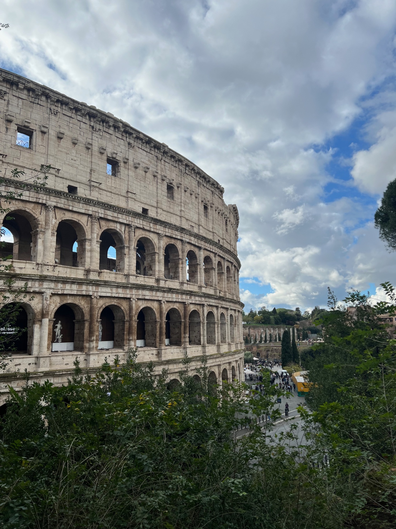 Rome — The Colosseum's arches against scattered clouds.