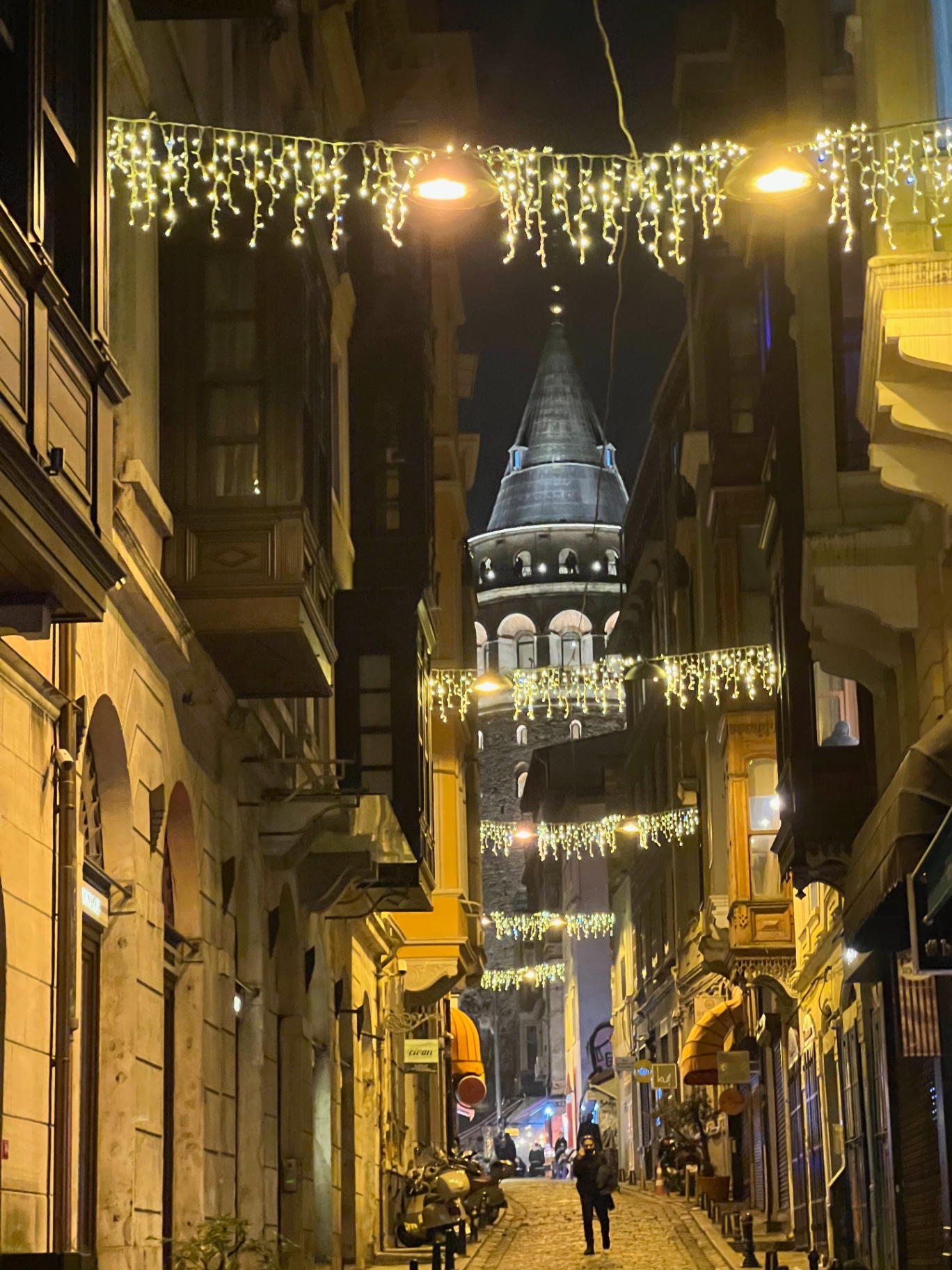 Istanbul — Galata Tower framed by festive lights in a narrow alley.