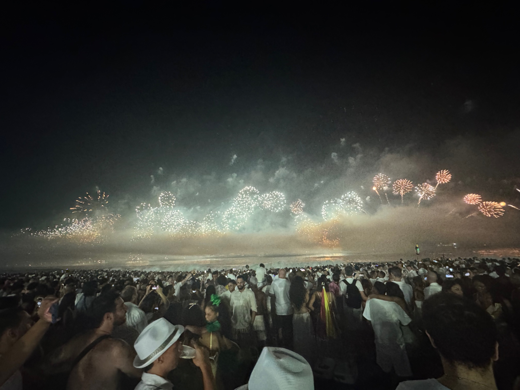 Rio de Janeiro — Réveillon crowds in white watching fireworks light up the bay.