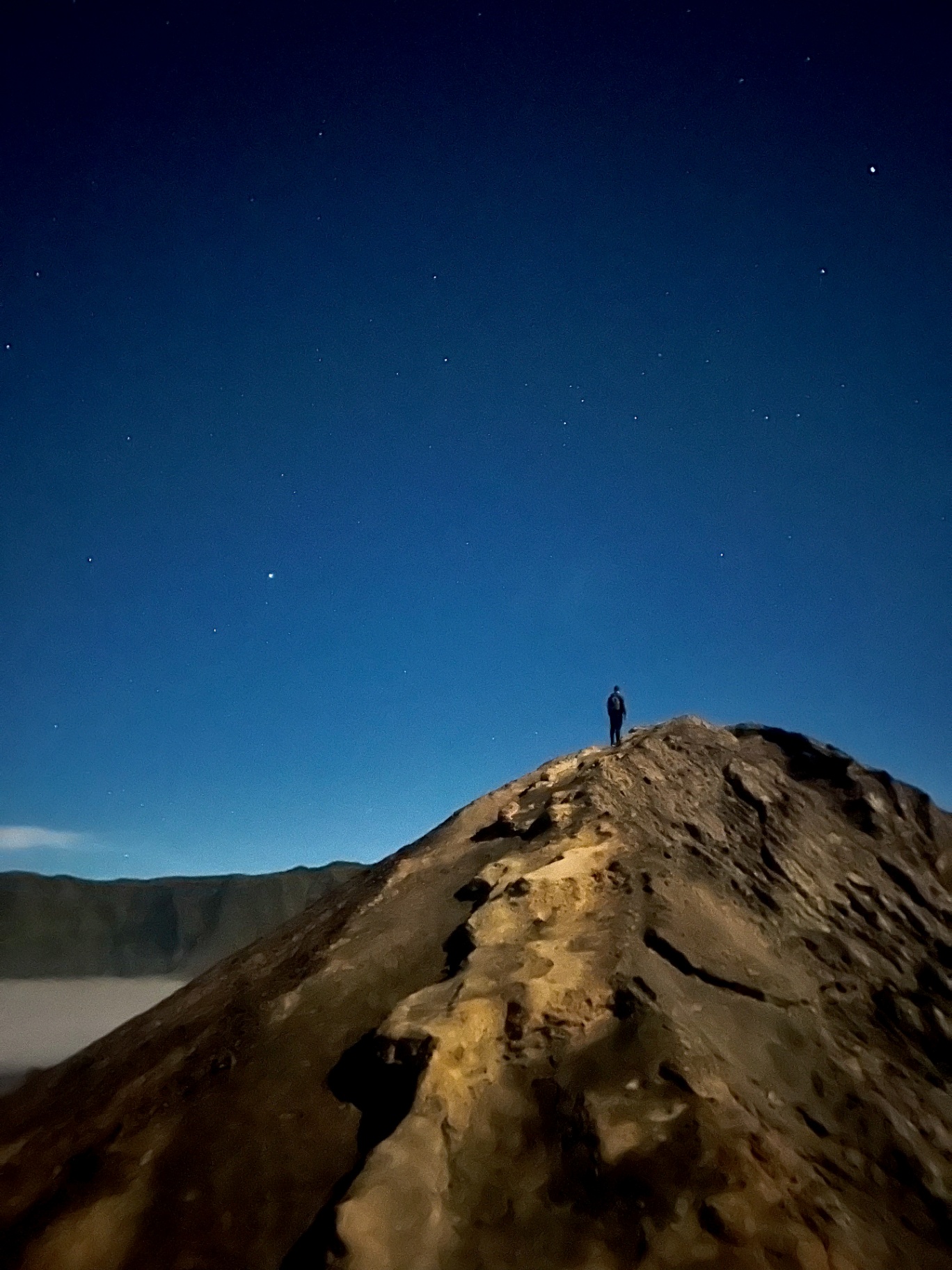 Mount Bromo — Tiny silhouette on the volcano ridge under a sky full of stars.