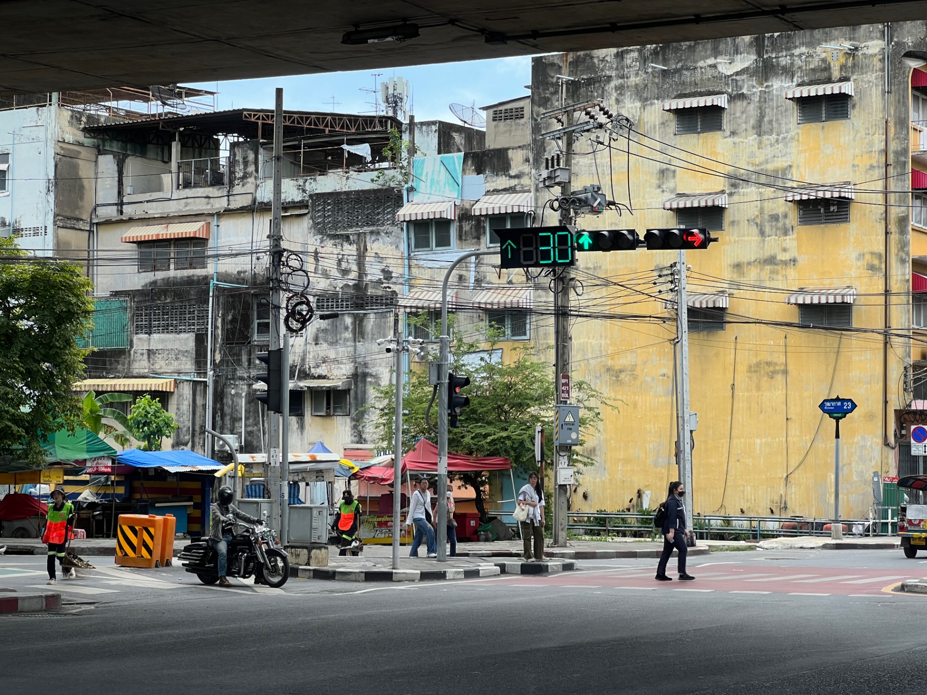 Bangkok — Quiet Bangkok intersection under the expressway, market stalls waking up.