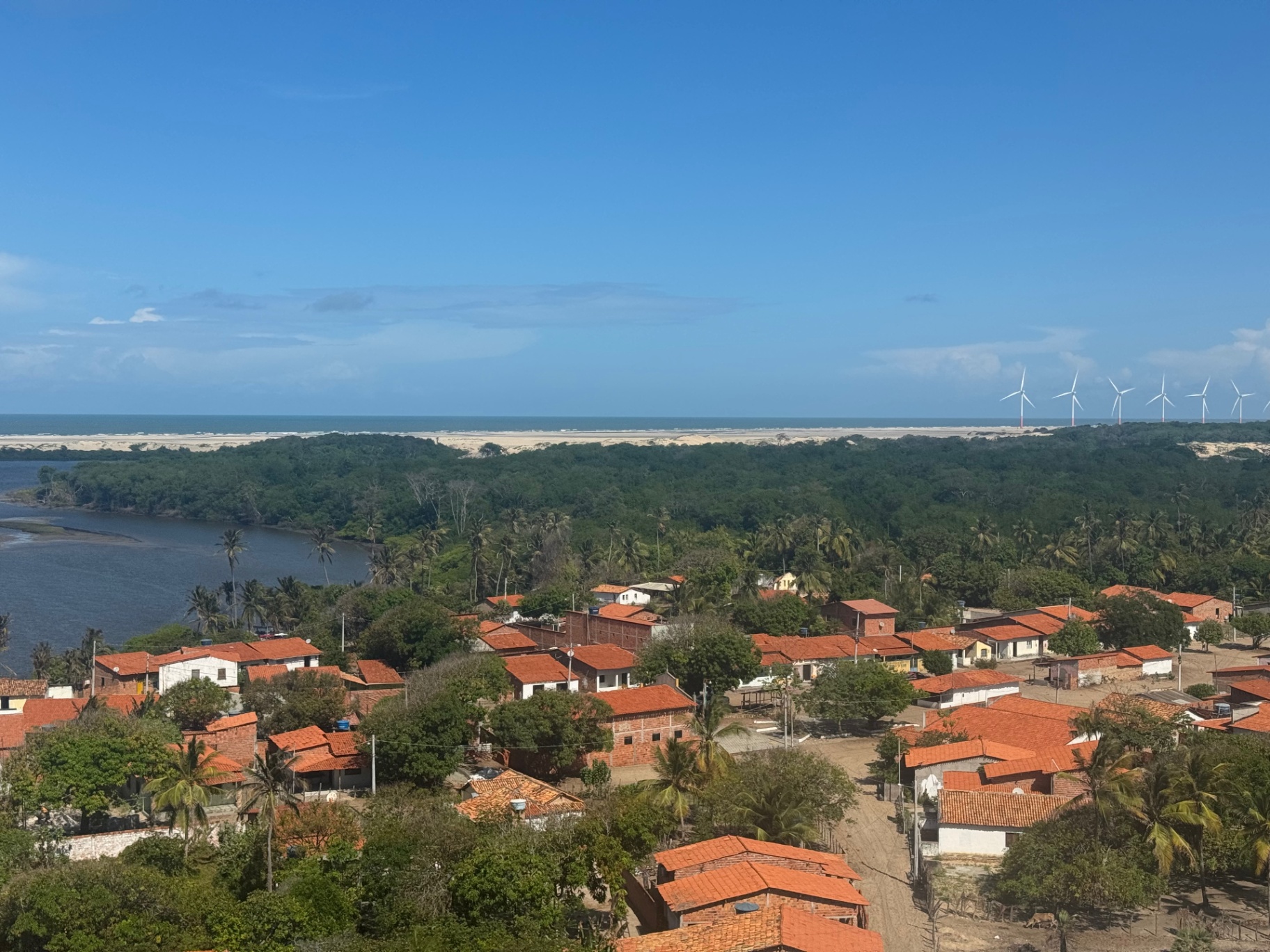 Lencois Maranhenses — Red rooftops, palm groves and distant dunes meeting the Atlantic.
