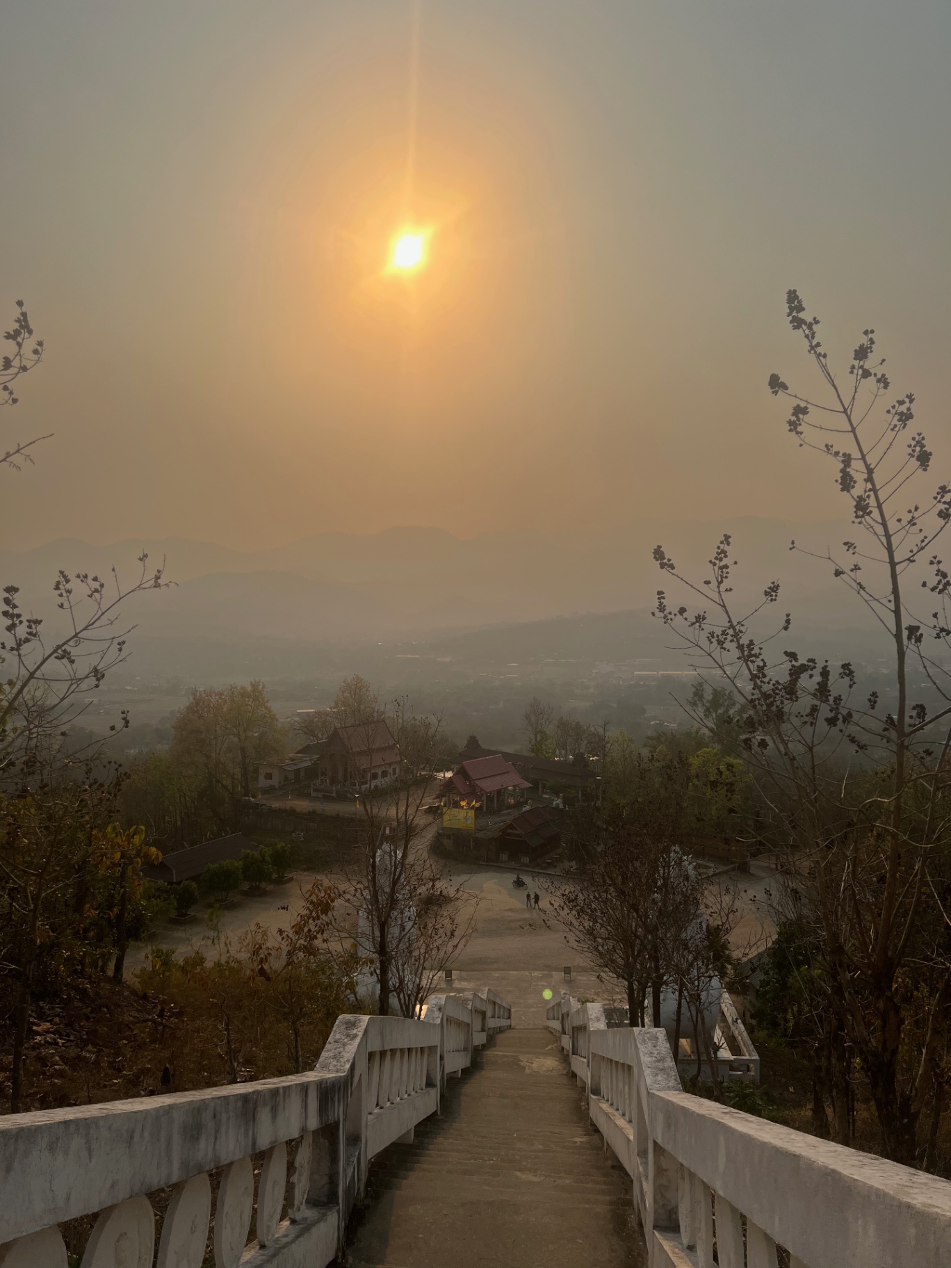 Pai — Sun sinking through the smoke haze from the Wat Phra That Mae Yen steps.