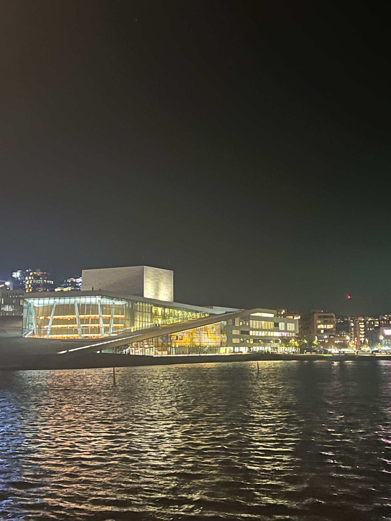 Oslo — Oslo Opera House glowing across the dark fjord.