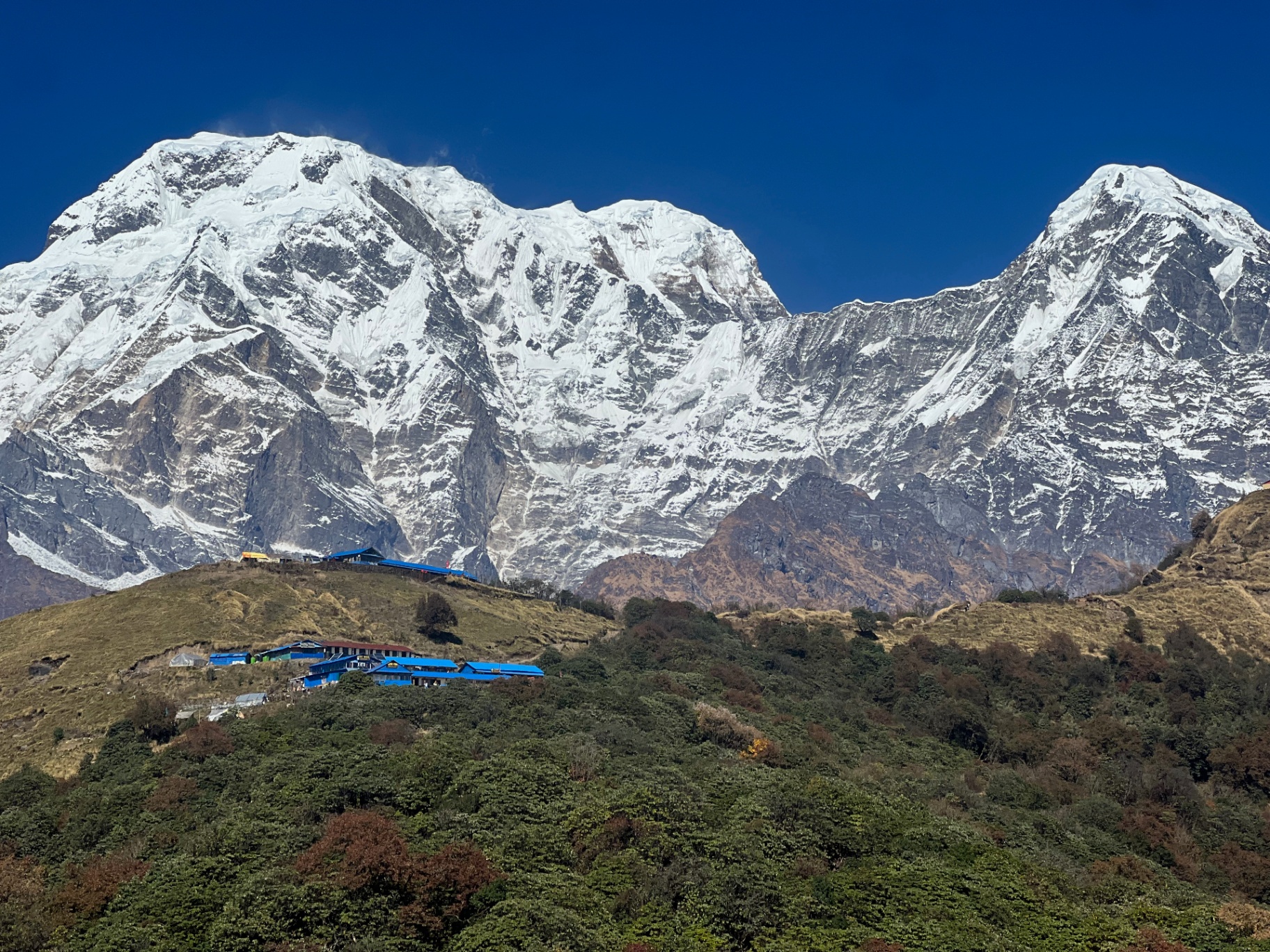 Pokhara — Annapurna South towering over a tiny ridge of blue-roofed teahouses.