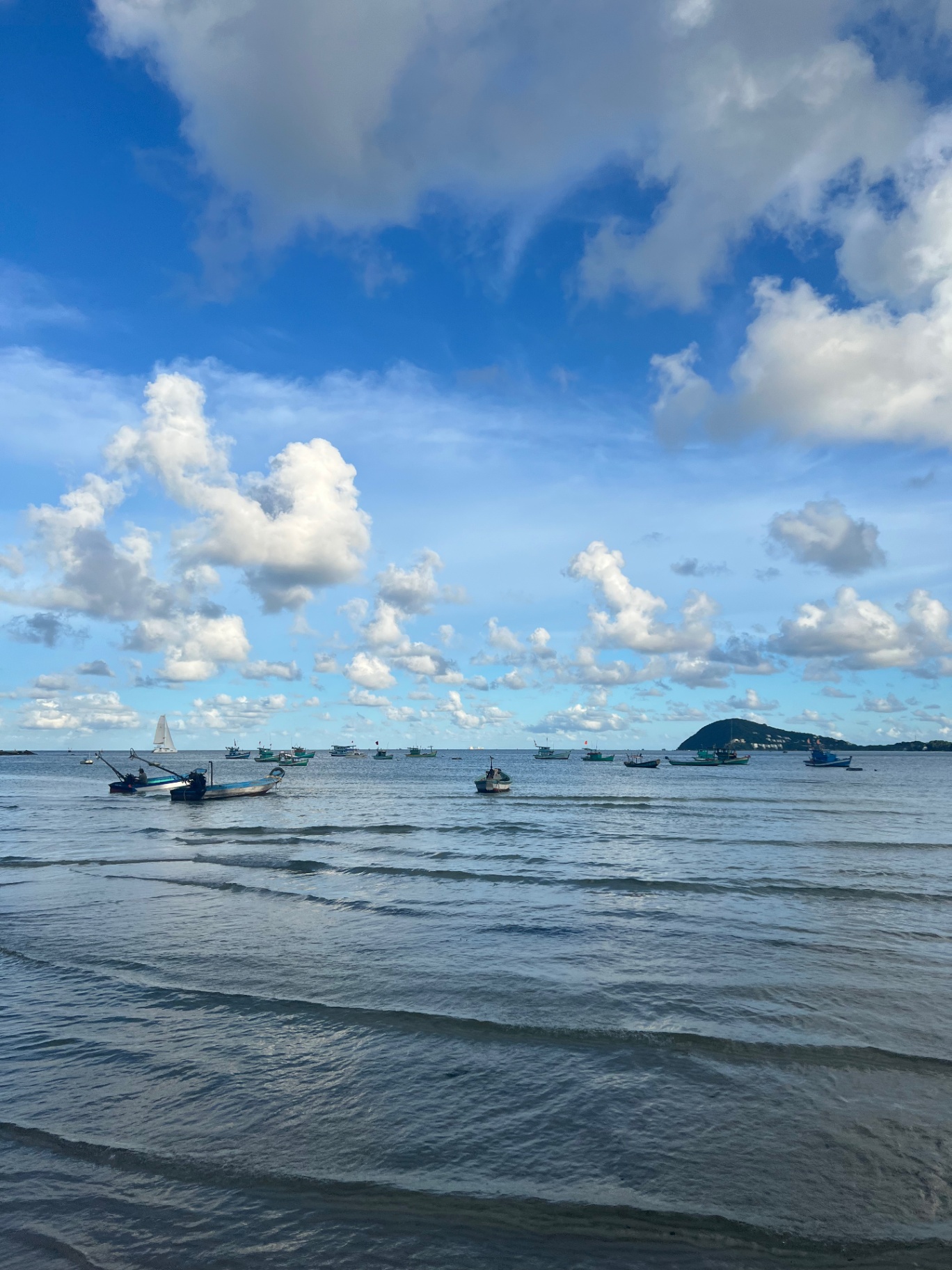 Phu Quoc — Fishing boats bobbing offshore beneath huge cotton-white clouds.