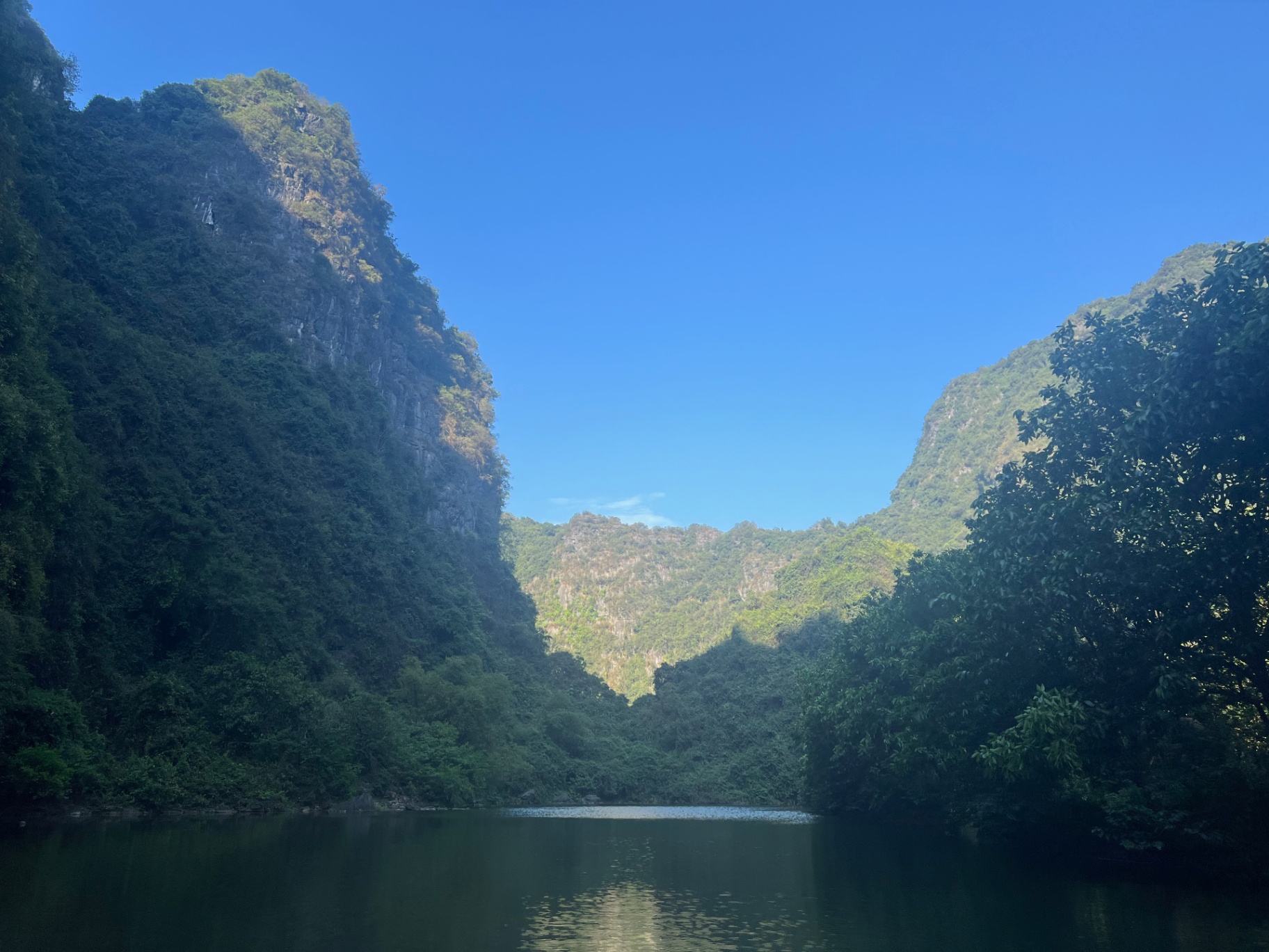 Ninh Binh — Glassy water threading between jungle-clad limestone peaks.