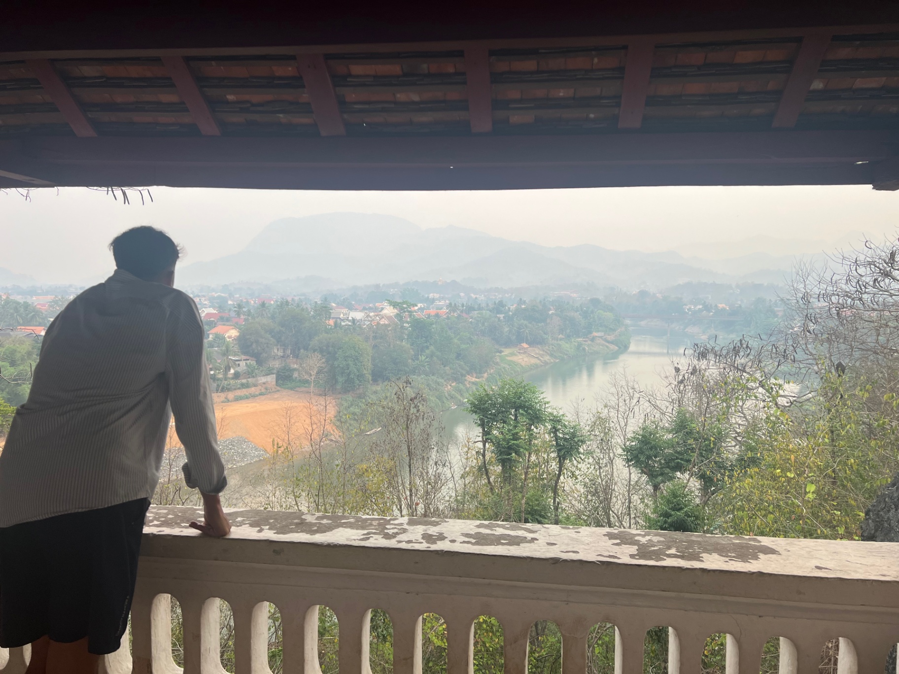Luang Prabang — Hazy Mekong valley view from a hilltop temple terrace.
