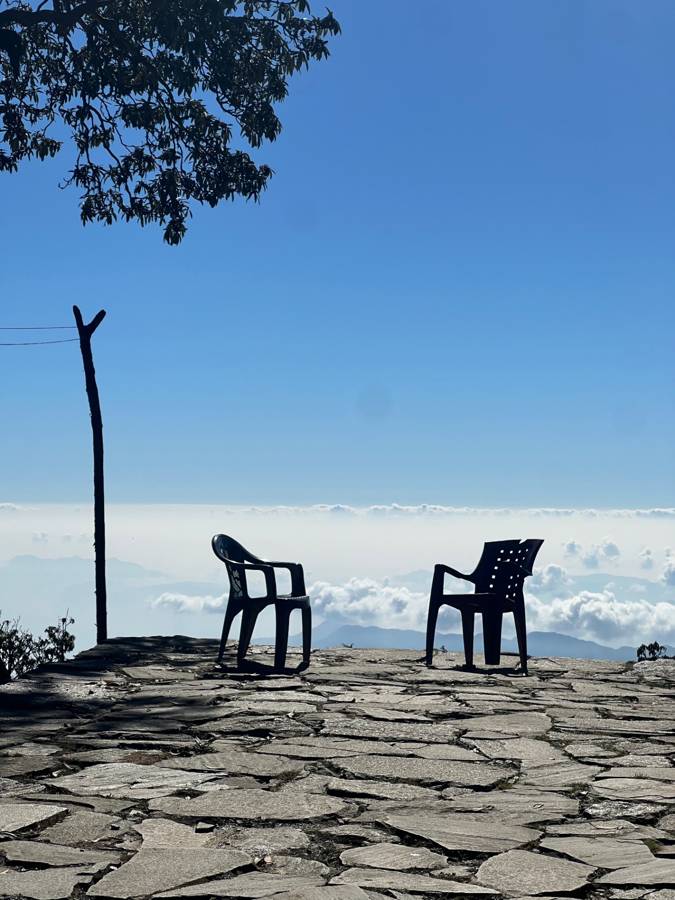 Pokhara — Two plastic chairs perched on a flagstone terrace above a sea of cloud.