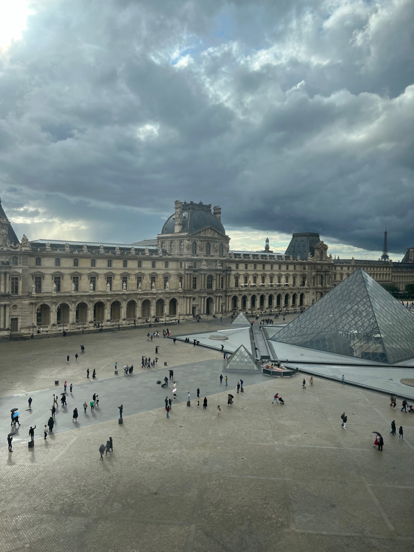 Paris — The Louvre pyramid under heavy Parisian clouds.