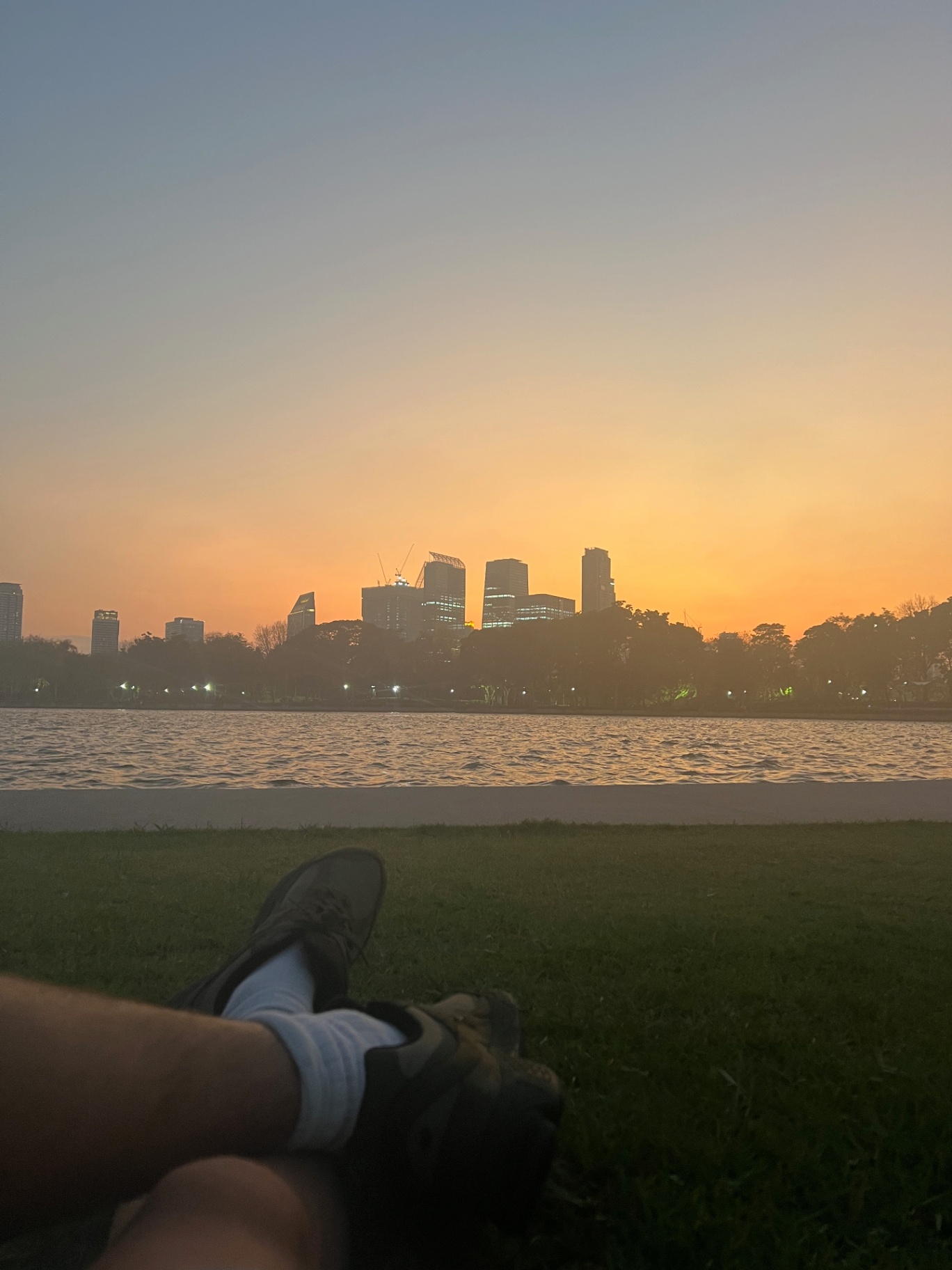 Bangkok — Sunset over Lumphini lake, skyline burning orange.