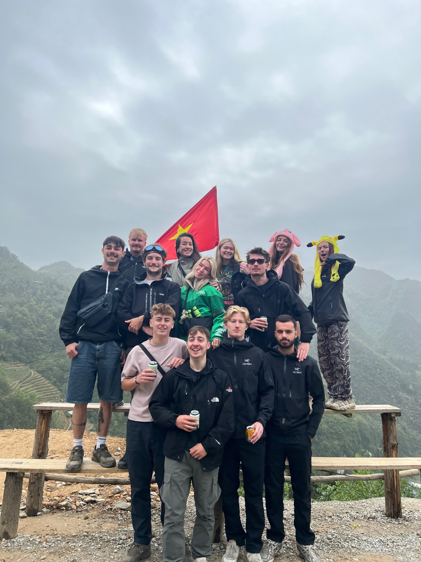 Ha Giang — The crew posing under the Vietnamese flag at a mountain viewpoint.