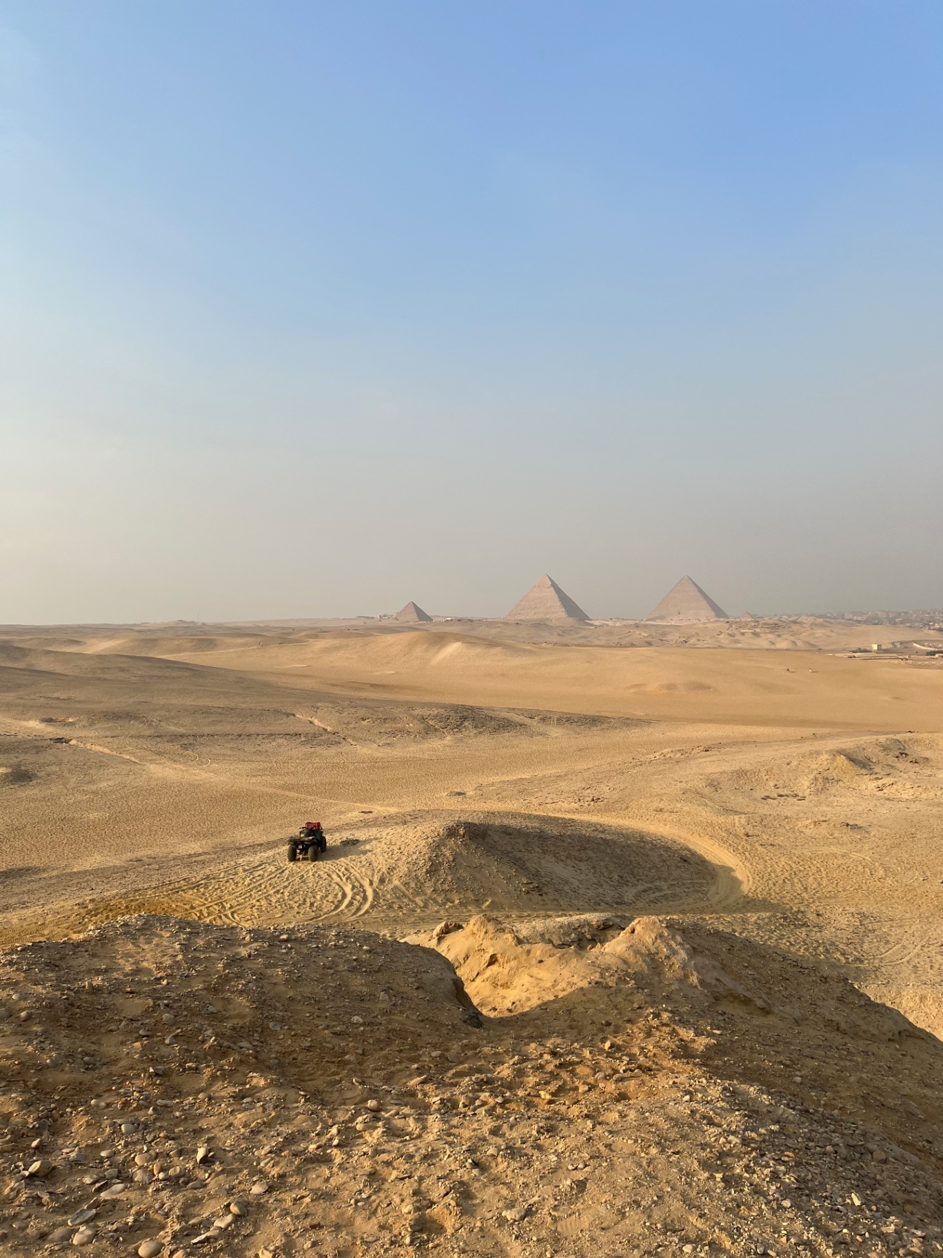Cairo — A lone quad in the dunes, pyramids in the distance.