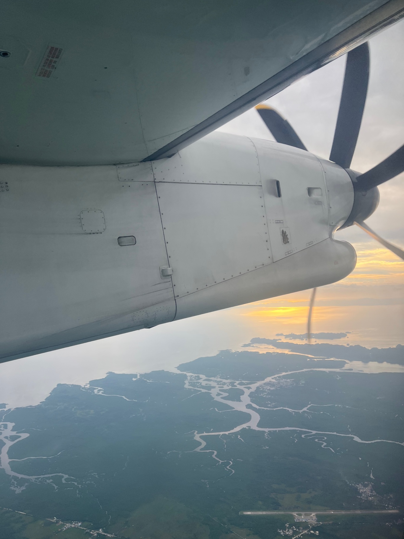 Siargao — Prop plane window — rivers braiding through the islands at sunset.
