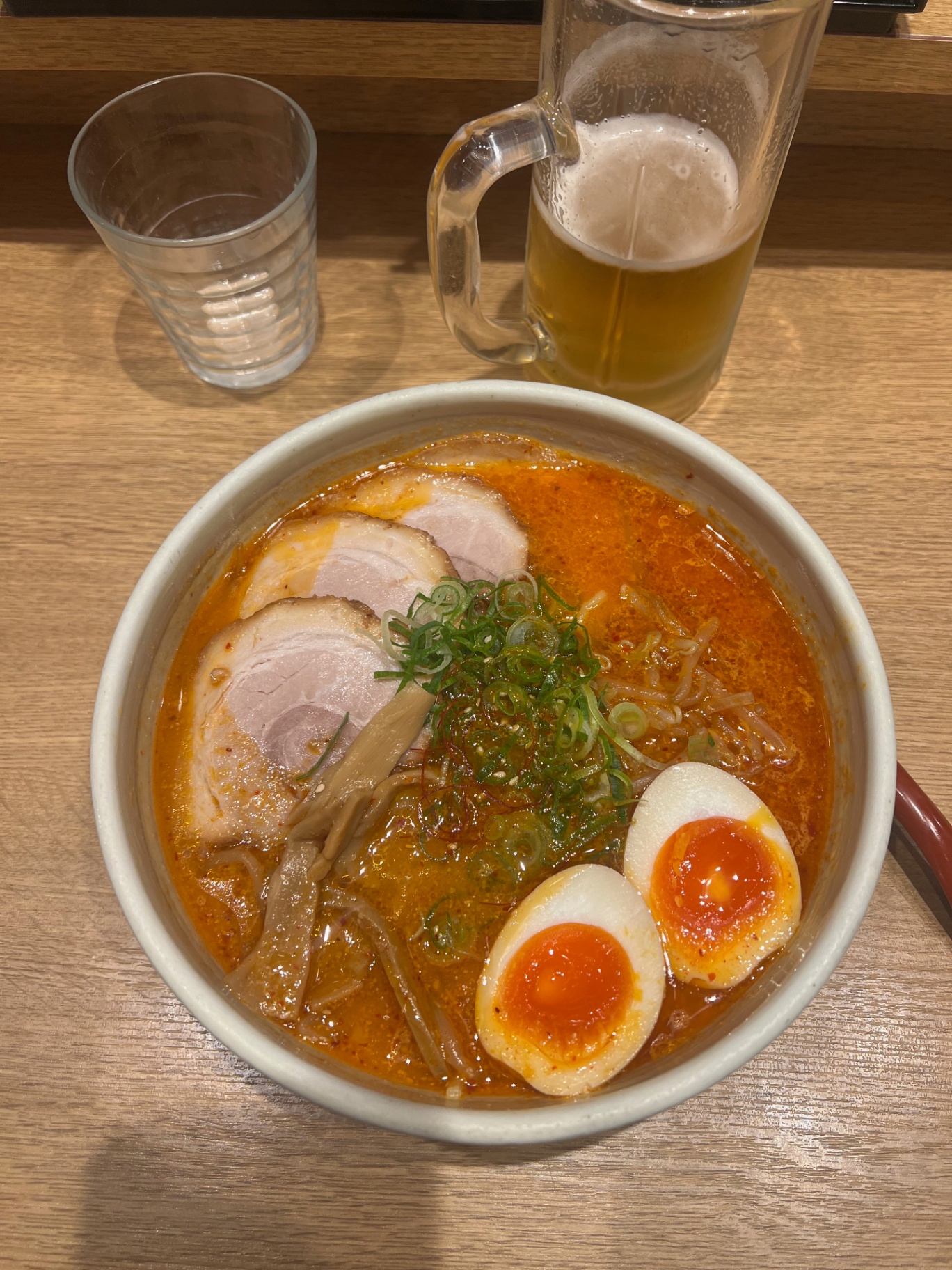 Tokyo — Late-night ramen and beer on a plain wooden counter.