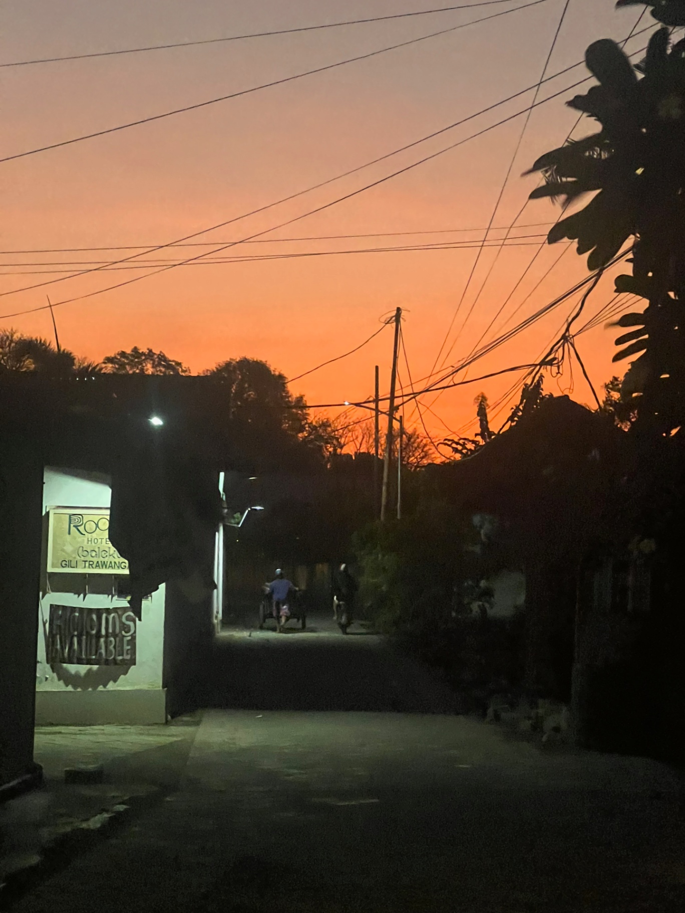 Gili Trawangan — Cidomo and scooters on a quiet island lane after dusk.