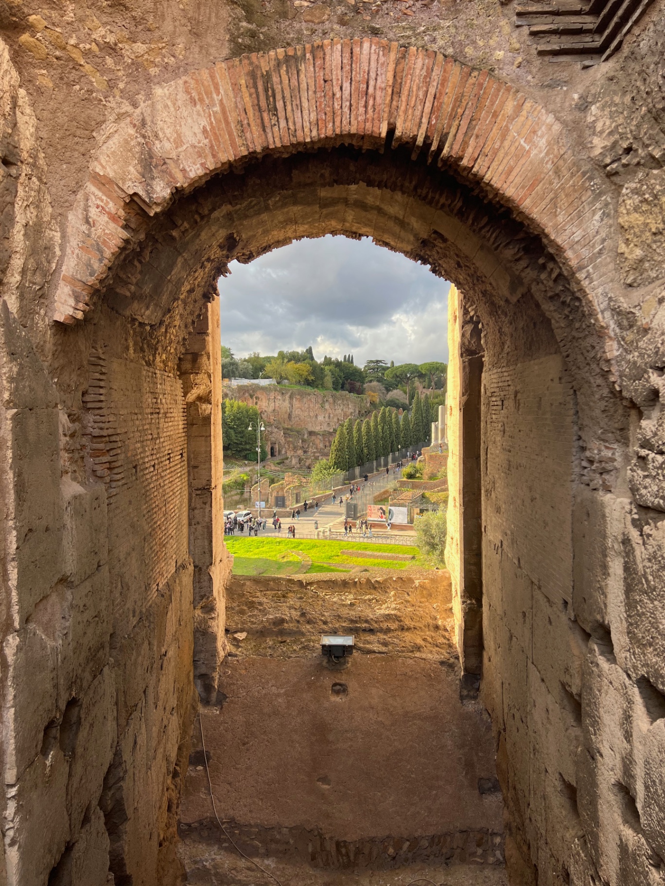 Rome — Palatine Hill framed by a Colosseum archway.