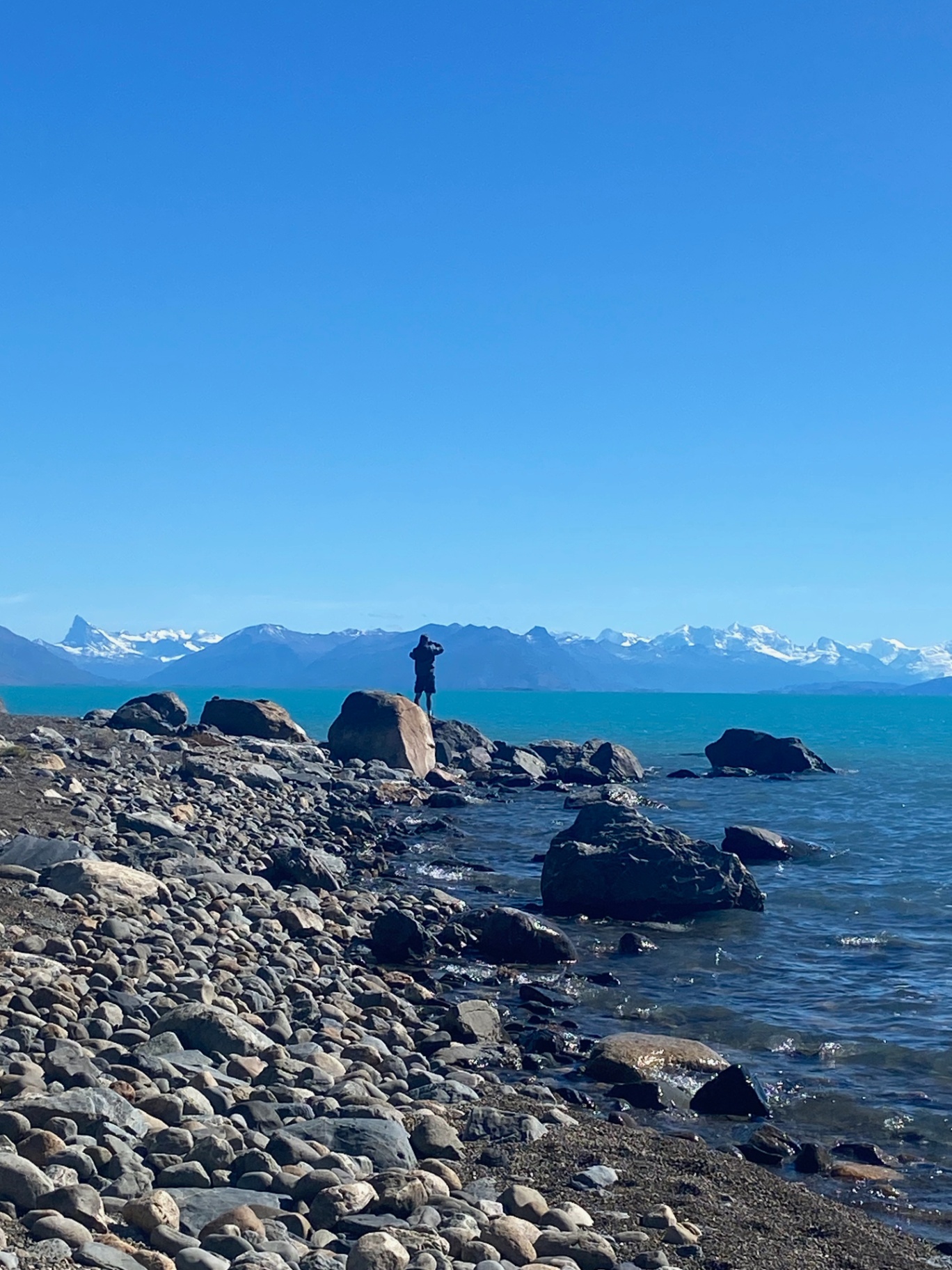 El Calafate — A lone figure on the shore of Lago Argentino, Andes beyond.