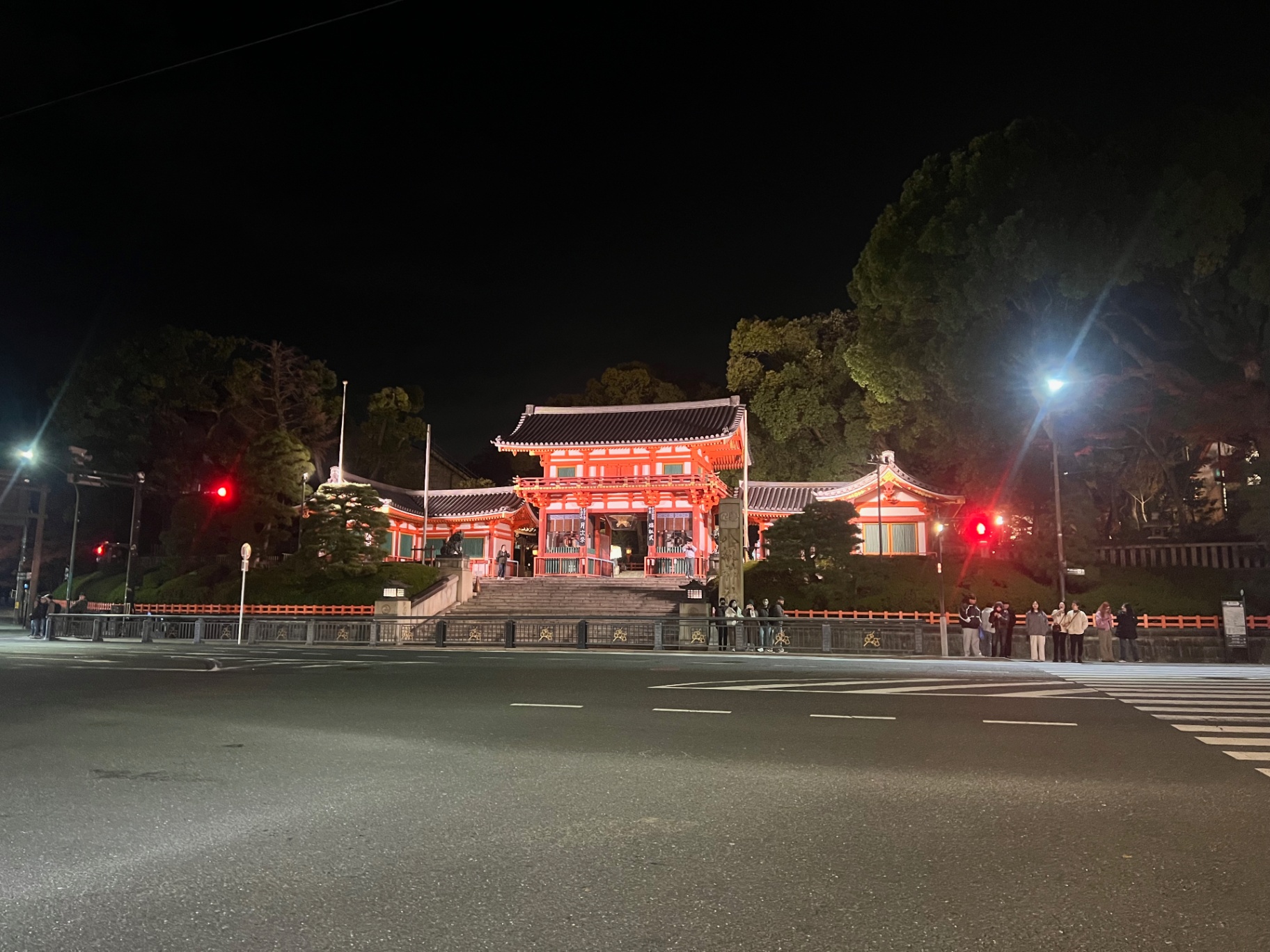 Kyoto — Temple gate glowing across the avenue after dark.