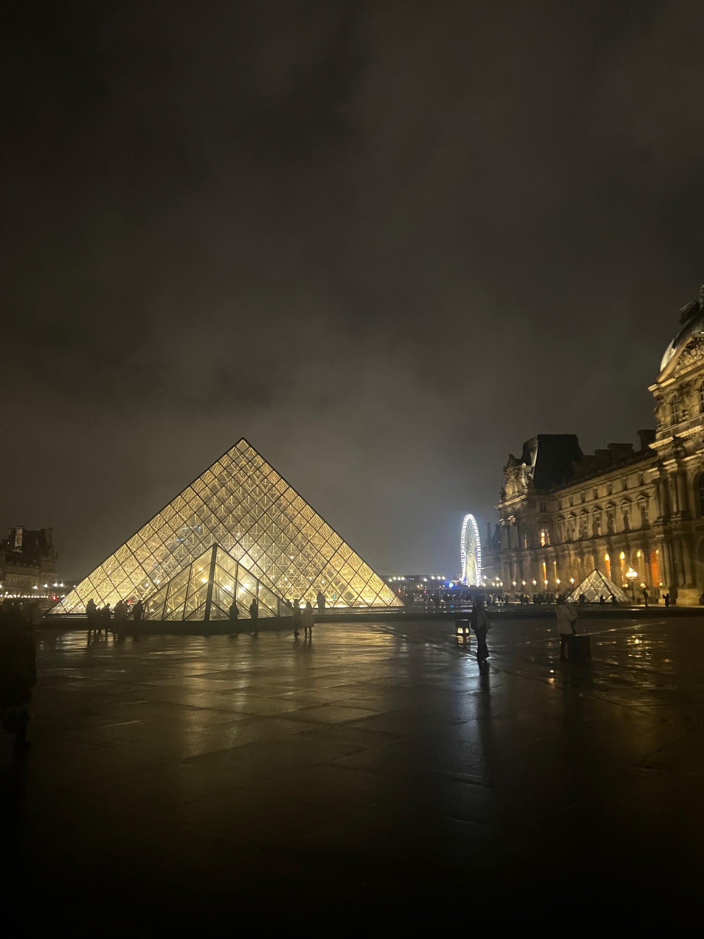 Paris — The Louvre pyramid glowing on a rainy Paris night.