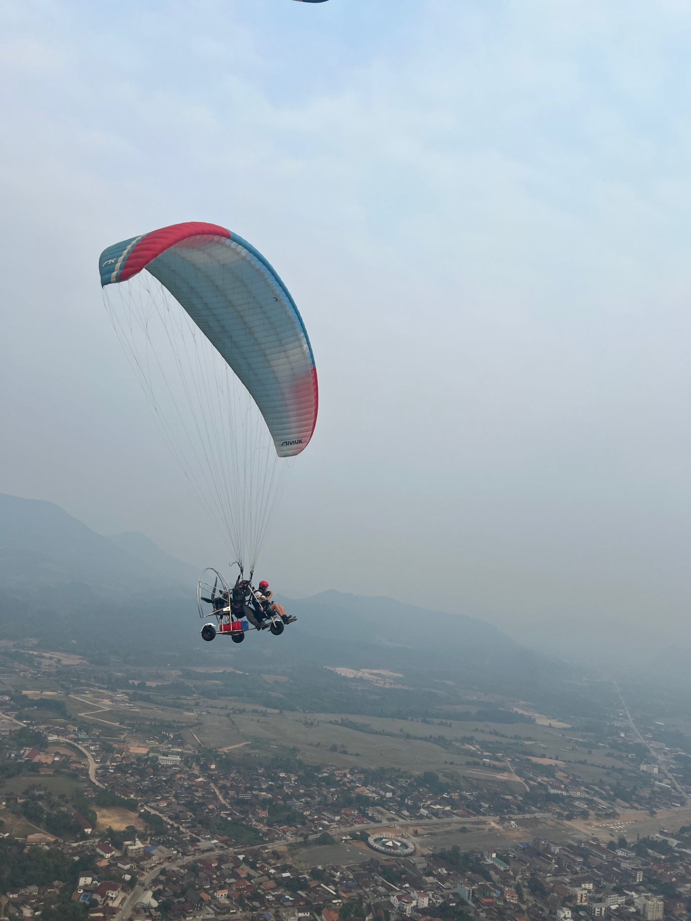 Vang Vieng — Powered paraglider drifting over Vang Vieng and the Nam Song valley.